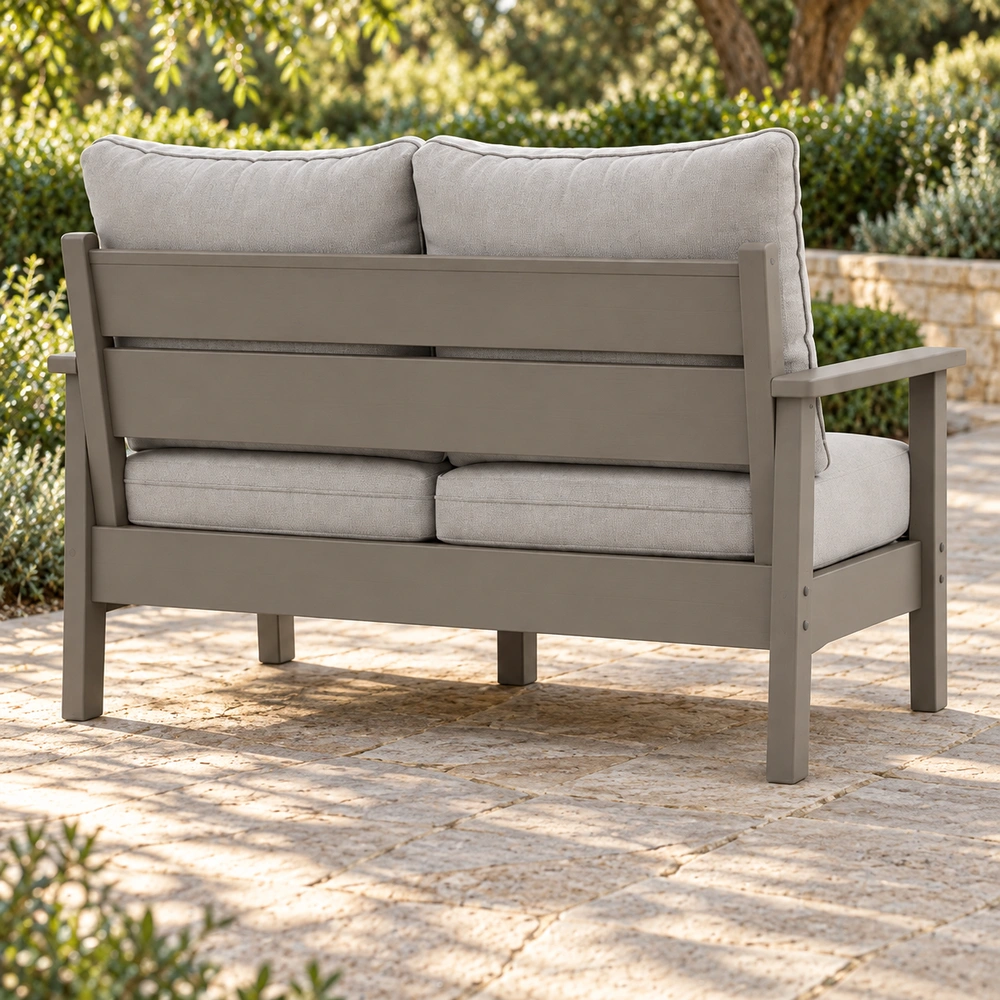 Two-seat cushioned HDPE outdoor sofa in a resort garden, rear-right view
